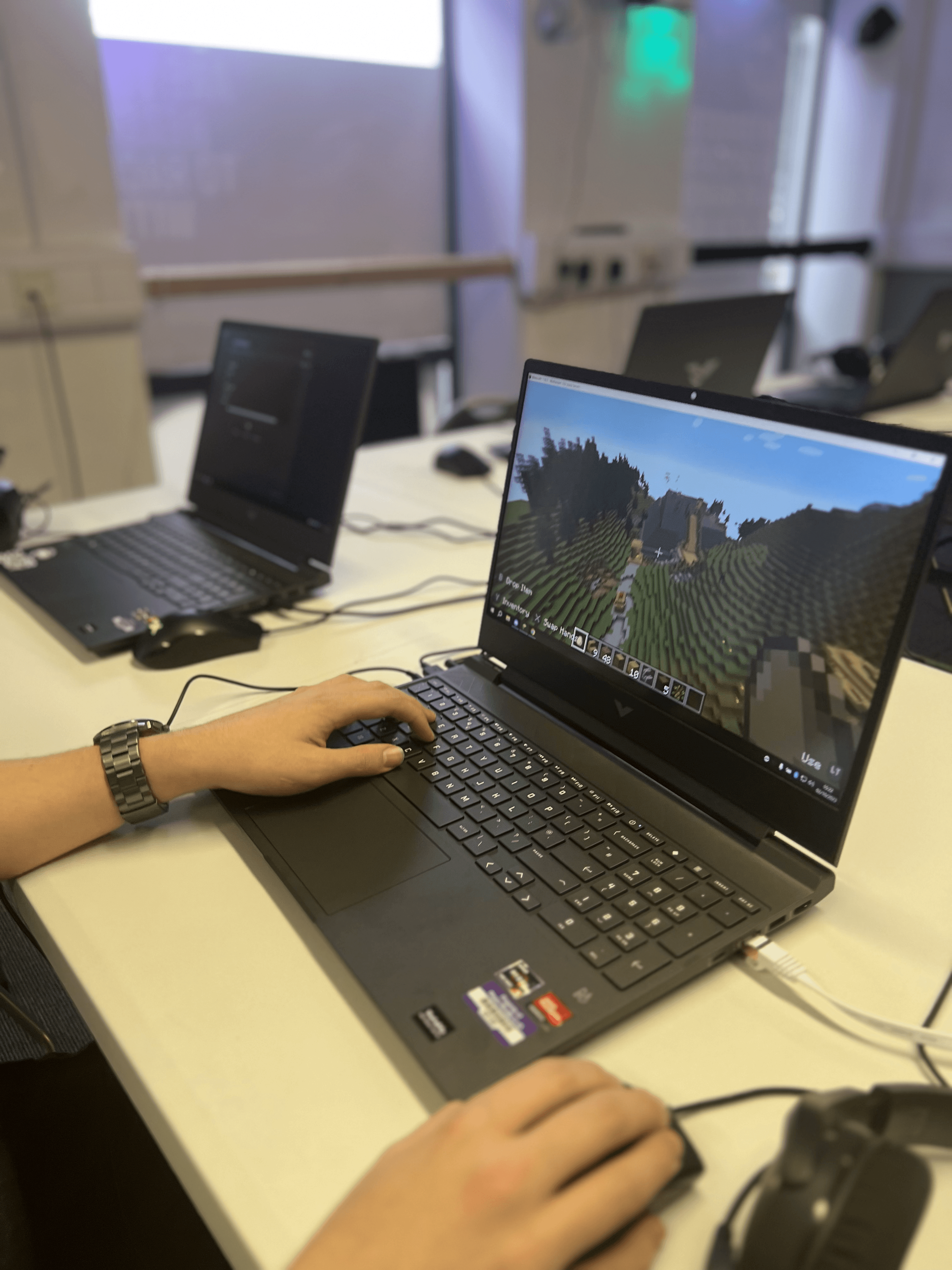 Young person's hands on keyboard during a Minecraft coding session